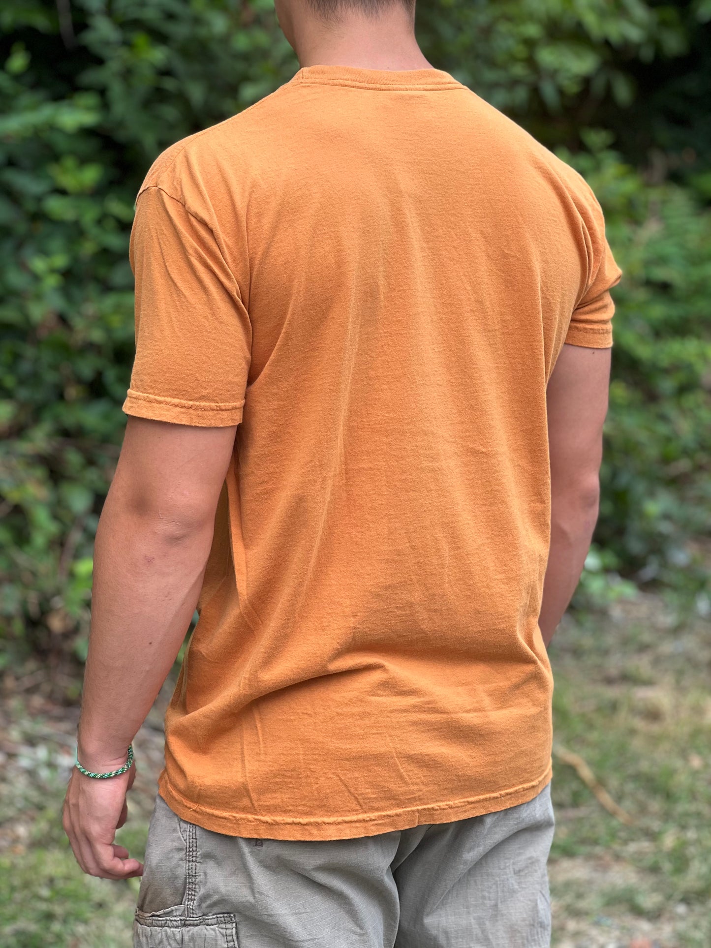 Person wearing a yellow t-shirt with a blurred green background