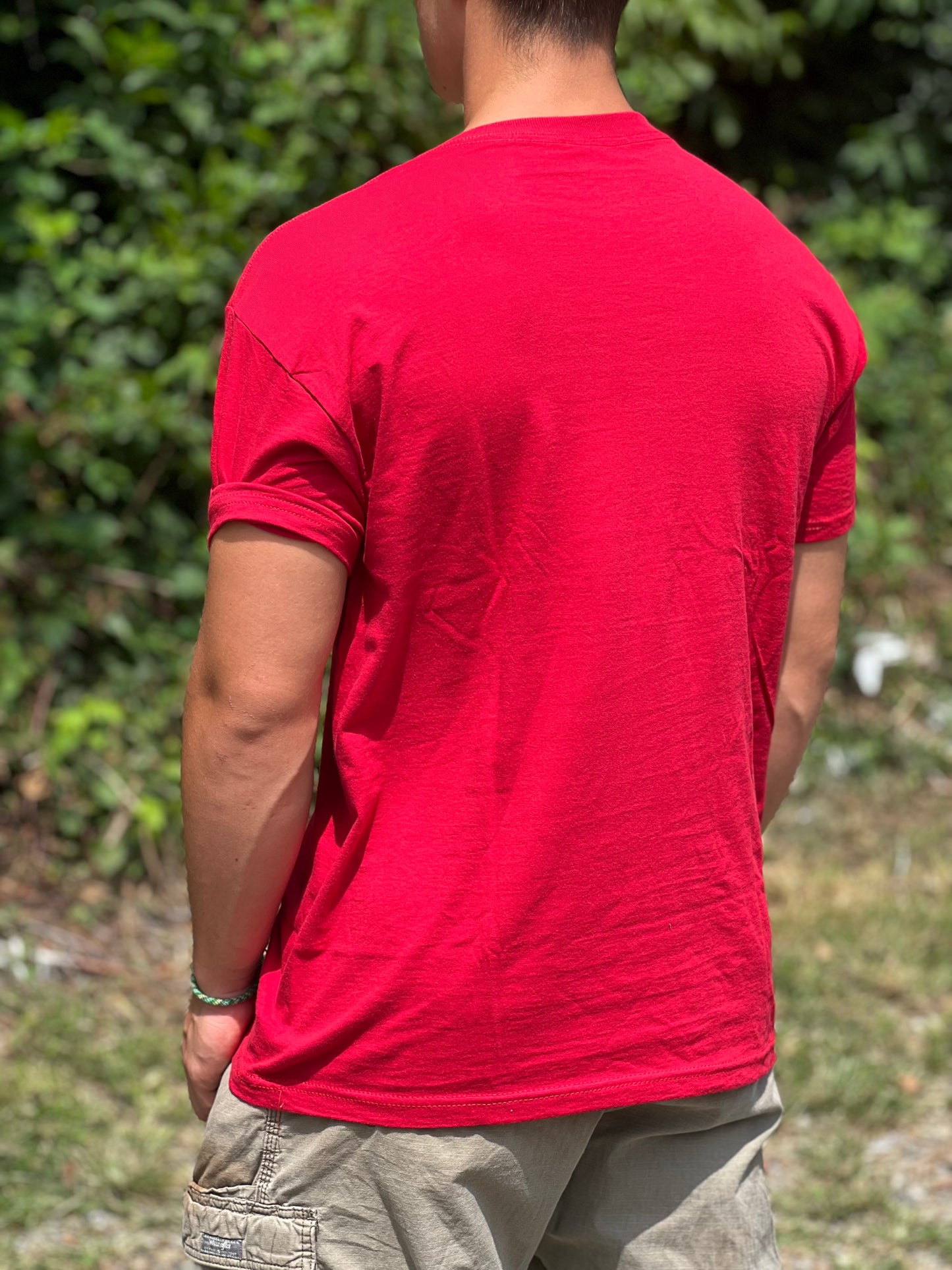 Person wearing a red t-shirt with a blurred natural background