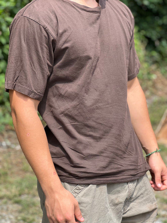 Person wearing a brown t-shirt and light gray pants outdoors