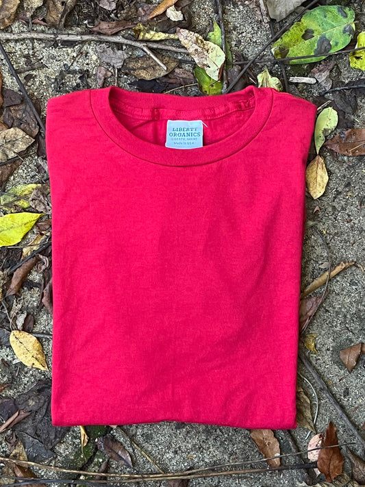 Organic cotton Red t-shirt on a ground surface with leaves