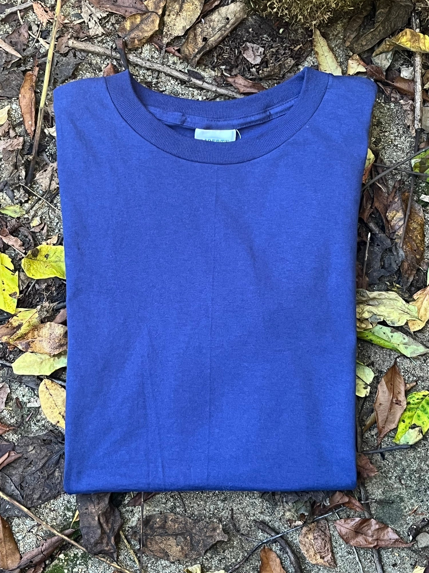 Organic cotton Blue t-shirt on a stone surface with leaves