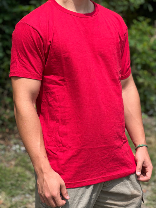 Person wearing a red t-shirt outdoors with greenery in the background